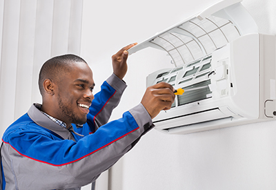 Happy Benchmark Service technician servicing and maintaining a ductless a/c system in Dallas-Fort Worth.