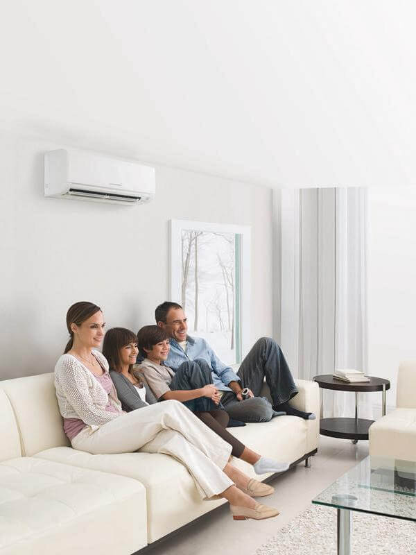 family relaxing on a couch in front of a new Mitsubishi HVAC system